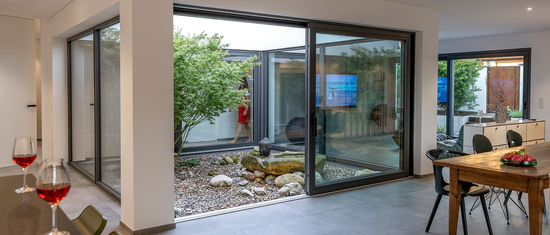 Freistehende Badewanne im Holzhaus mit direktem Blick in den begrünten Innenhof des Atriumhauses 